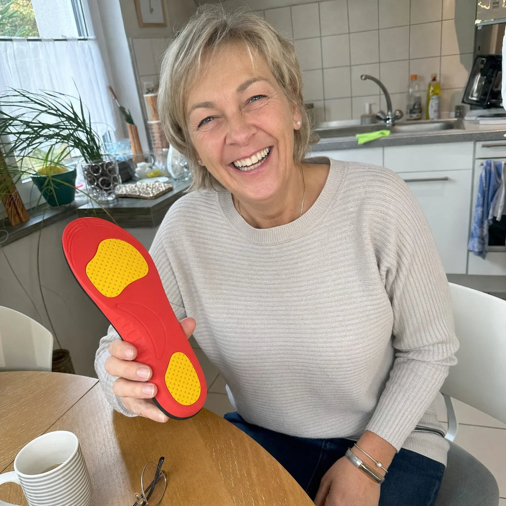 Laura laughing at her kitchen table while holding an Ortavio ArcCore insole