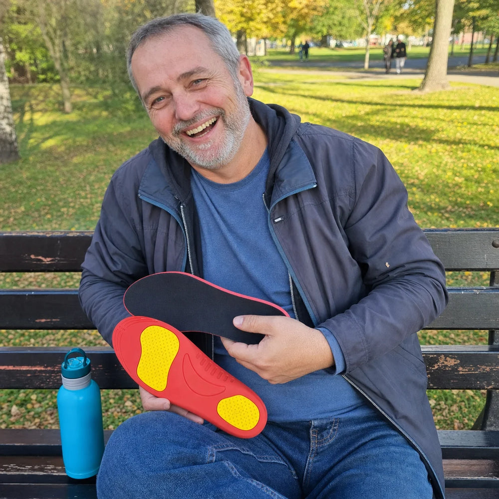 Peter laughing on a park bench while holding Ortavio ArcCore insoles