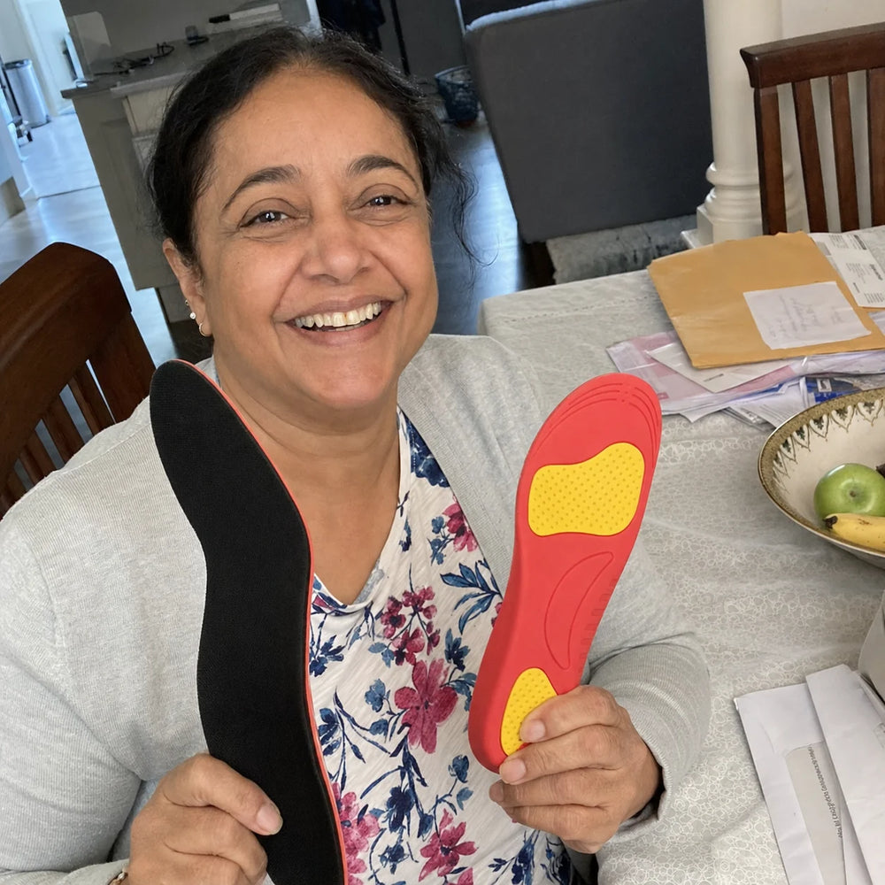 Ines laughing at her dining table while showing Ortavio ArcCore insoles
